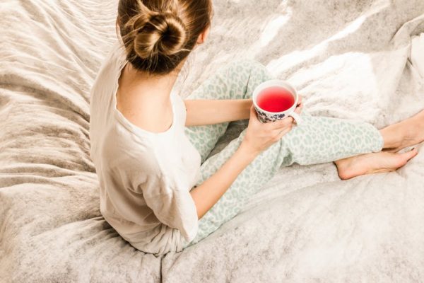 a girl with a warm drink sitting in bed